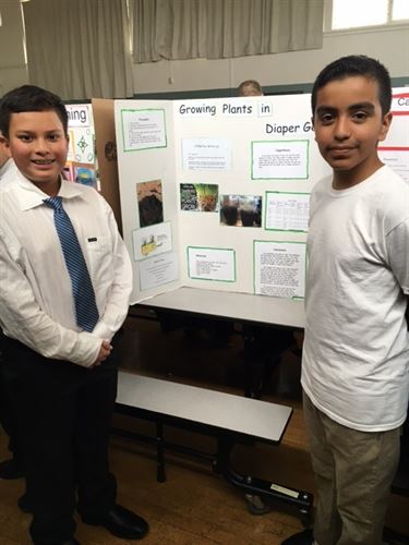 Two boys presenting their science fair project board.