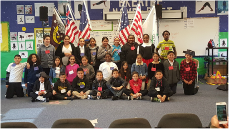 Group of students in front of of a classroom posing in front of Flags.